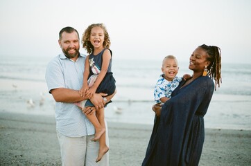 Happy biracial family on beach at sunset