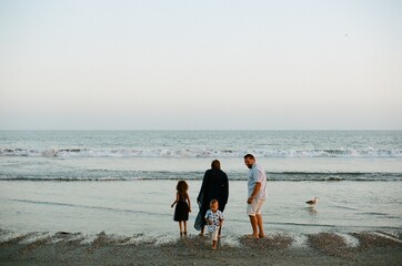 Family wading in ocean at sunset