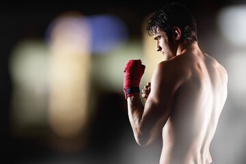 Sports handsome male boxer fighting on dark background with smoke.