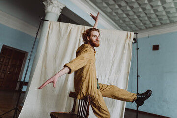 
young red-haired guy steps on a background of light fabric