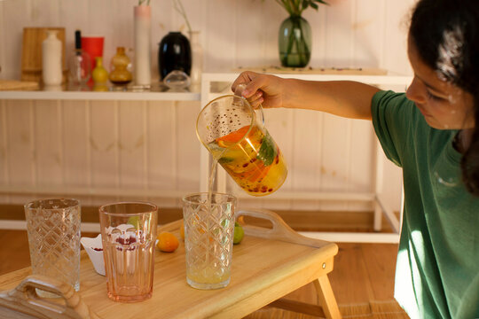 A girl is pouring a lemonade in a glass 