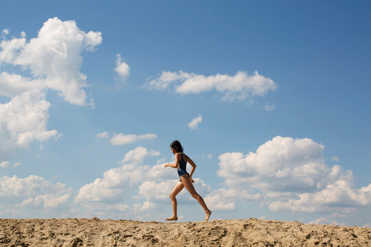 Cute girl is running on a sand 