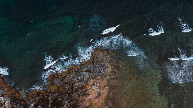 Ocean waves reach the rocks near the cliff