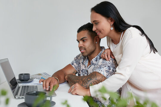 Young couple at home shopping online together on their laptop