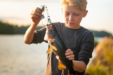 Boy intent and focused holding fish he caught on fishing trip
