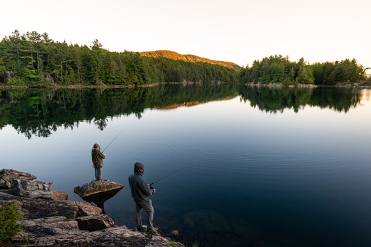 Father and Son Fishing at Lake with Sunset over Mountain Ridge on Back Country Family Canoe Trip