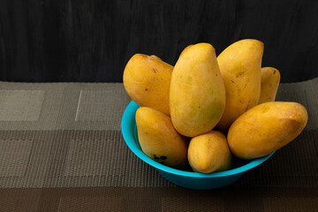 Mangos manila maduros en un plato azul con un fondo de color negro