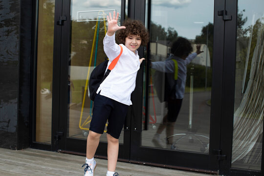 Cute school boy is standing on a threshold of a school.