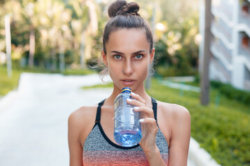 Sportswoman drinking water during training in summer