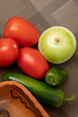Jitomates, chiles y cebollas, para hacer salsa mexicana con un fondo café.