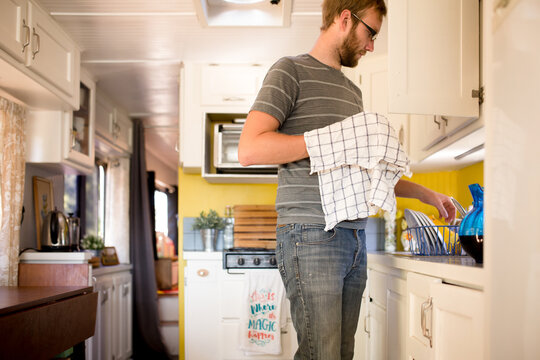 Man dries dishes in tiny kitchen