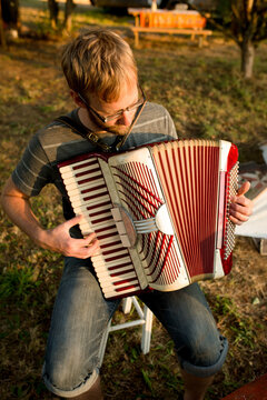 Bearded man plays accordion outdoors