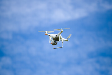 White drone in the blue sky with gentle clouds.