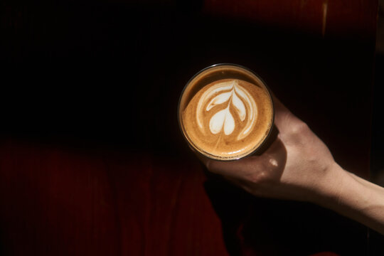 Crop person showing cup of fresh latte