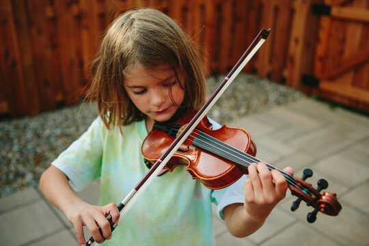little girl plays the violin outside 