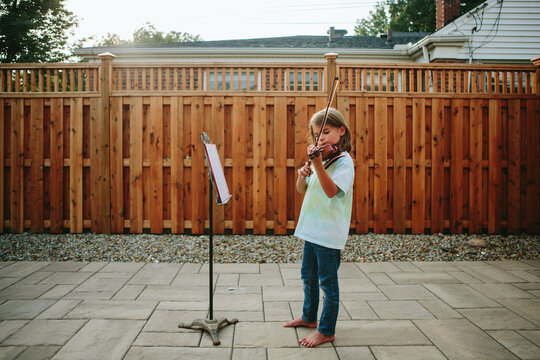 little girl plays the violin outside 