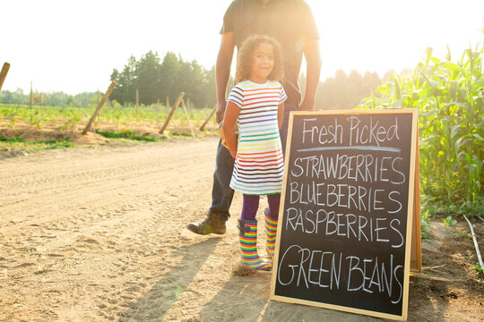 Smiling girl stands next to sign. 