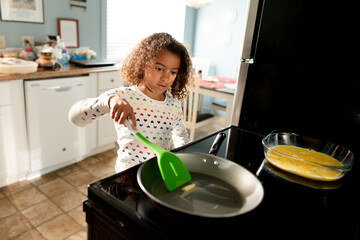Curly haired girl melts butter in a pan