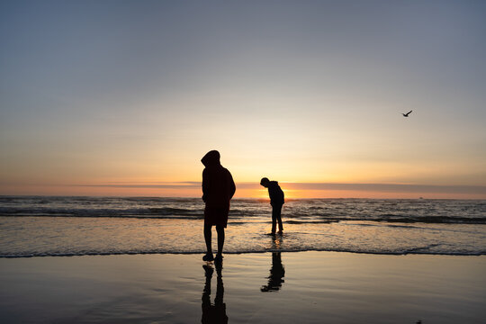 Boys wade in ocean  on Cannon Beach at sunset 
