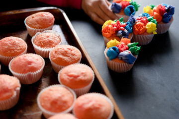Homemade pink cupcakes on a tray with child’s hand
