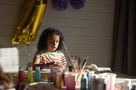 Girl paints at a table during a birthday party
