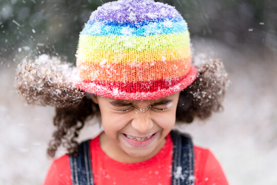 Cute girl in rainbow cap squints in snowy breeze