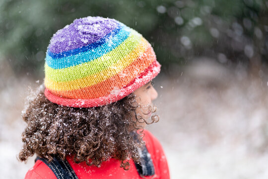 Curly haired girl in rainbow hat in snow