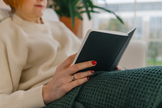 literature and people concept - woman reading book at home
