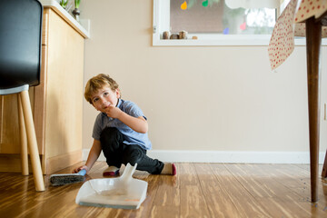 Boy with broom crouches on bamboo floor
