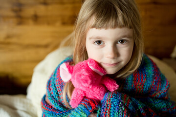 Girl holding stuffed animal looks up at camera