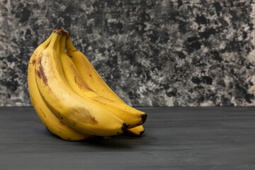 Racimo de plátanos maduros con un fondo vintage color gris