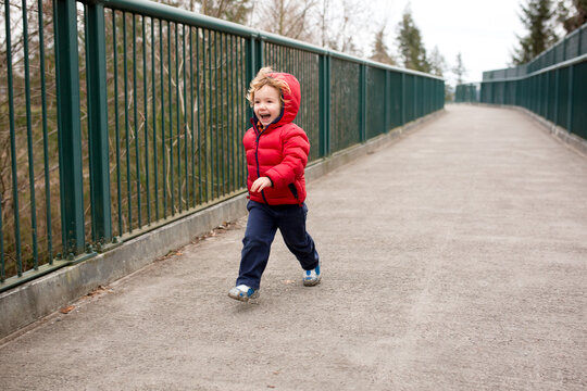 Cute boy in coat runs down urban path