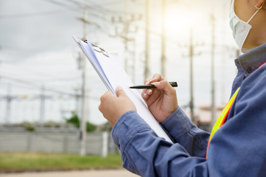 Hand holding clipboard and write on document checklist high voltage system, Working woman