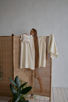  woman stands behind a bamboo screen and changes into a white cotton robe