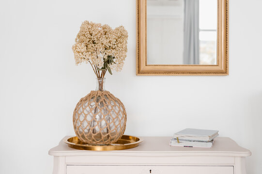 Vase and books on cupboard near mirror