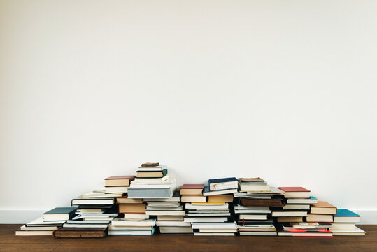 Stacked books against a white wall