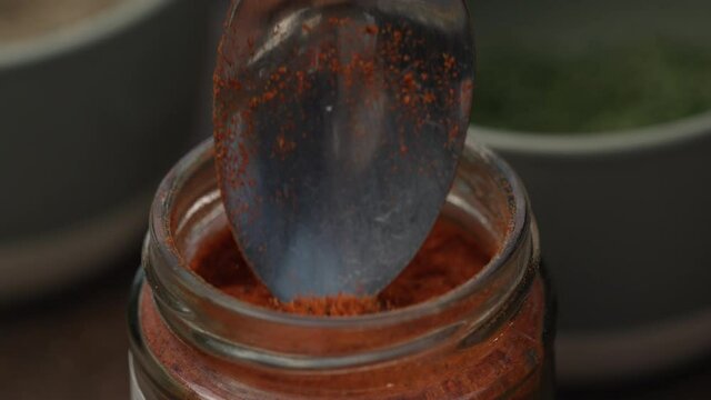 Scooping Paprika Powder Using Tablespoon. - Close Up Shot