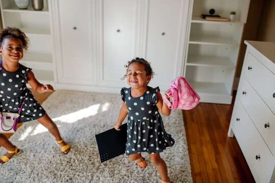 Biracial sisters dancing in empty bedroom