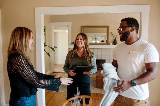 Smiling biracial couple discussing home tour with happy real estate agent
