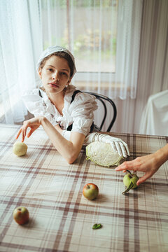 romantic girl sitting at a table among apples
