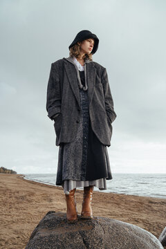 woman in warm stylish clothes stands on a stone
