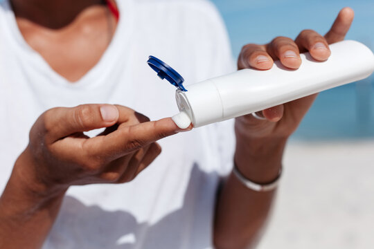 Crop woman applying sunscreen cream in summer