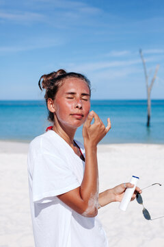 Sunburned Woman applying suntan lotion on beach