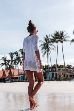 Slim woman walking on seashore in summer