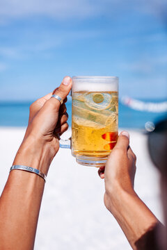 Crop woman with glass of beer on beach