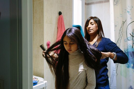 10-year old hispanic girl getting her hair untangled by her mother