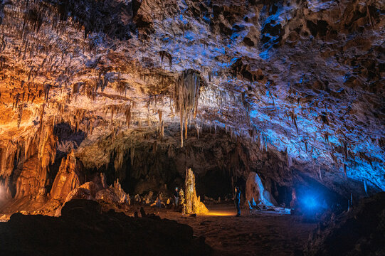 Speleologists admiring rocky calcite cave 