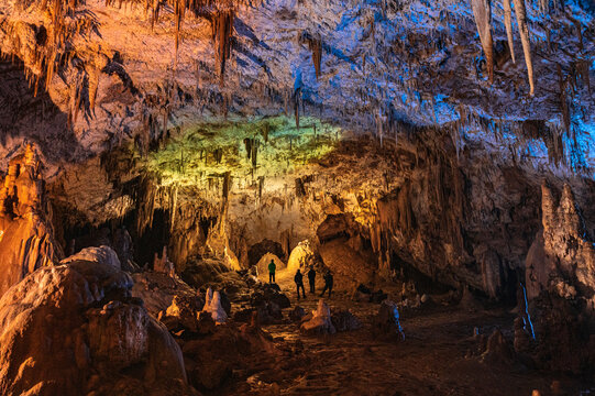 Group of speleologists exploring rocky cave 