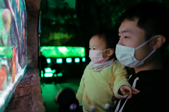 Father and daughter wearing masks visiting the aquarium