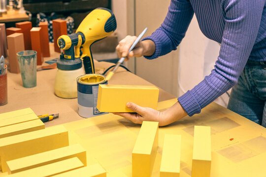 Woman painting blocks in yellow detail